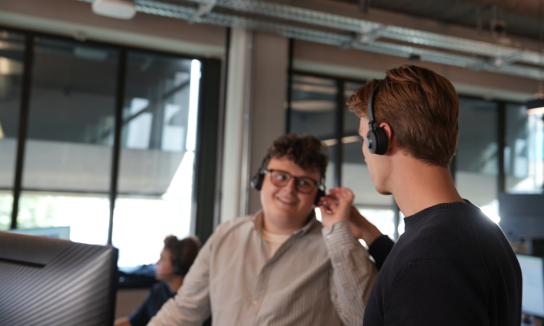 En kollega retter headsettet på en SDR, begge smiler